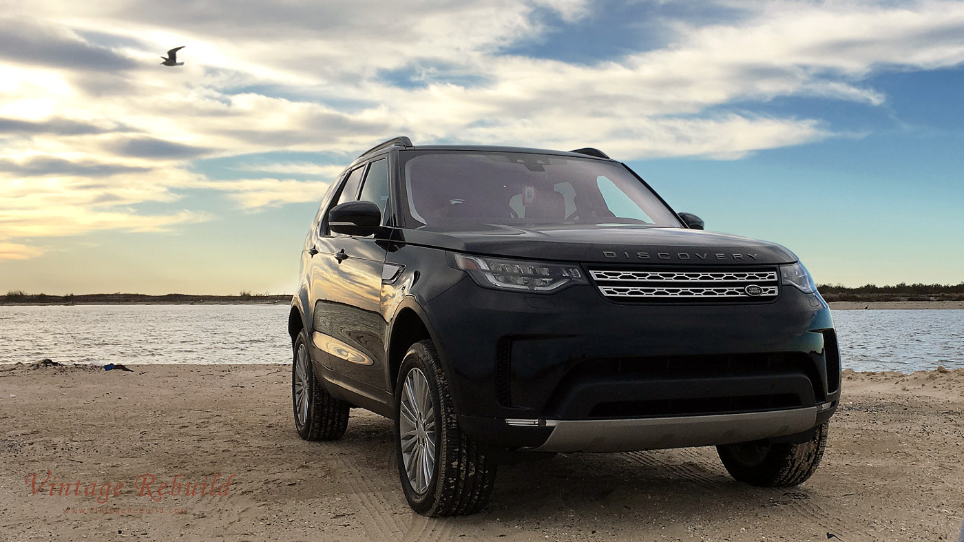 Black 2017 Land Rover Discovery HSE Luxury SUV offroad driving on beach sand at sunset, Jetty Park, Matagorda, Texas.