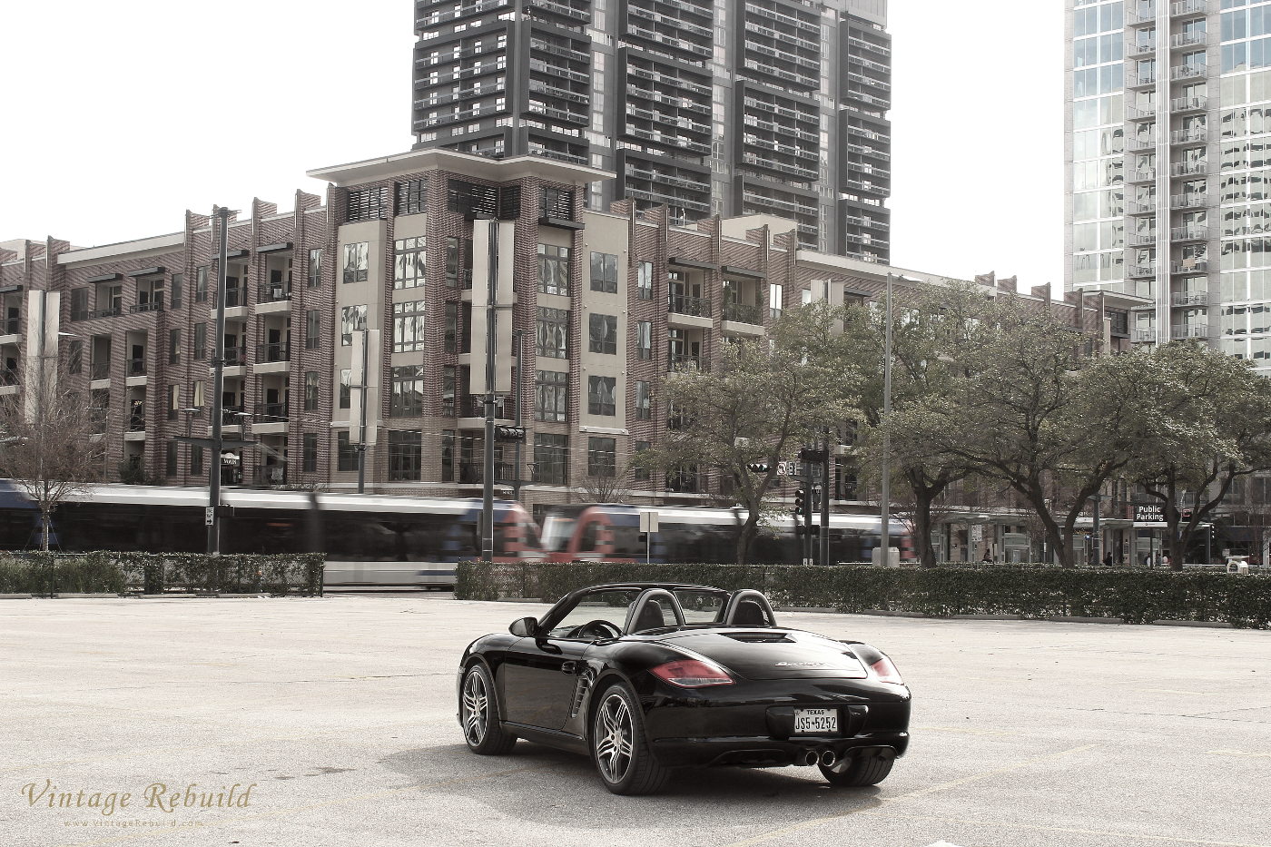 Black Porsche Boxster S 98.2 Photo Main Street Houston City with Train. German luxury car, the 987.2 Porsche Boxster S. A black Porsche Boxster S, 987.2 generation Boxster.