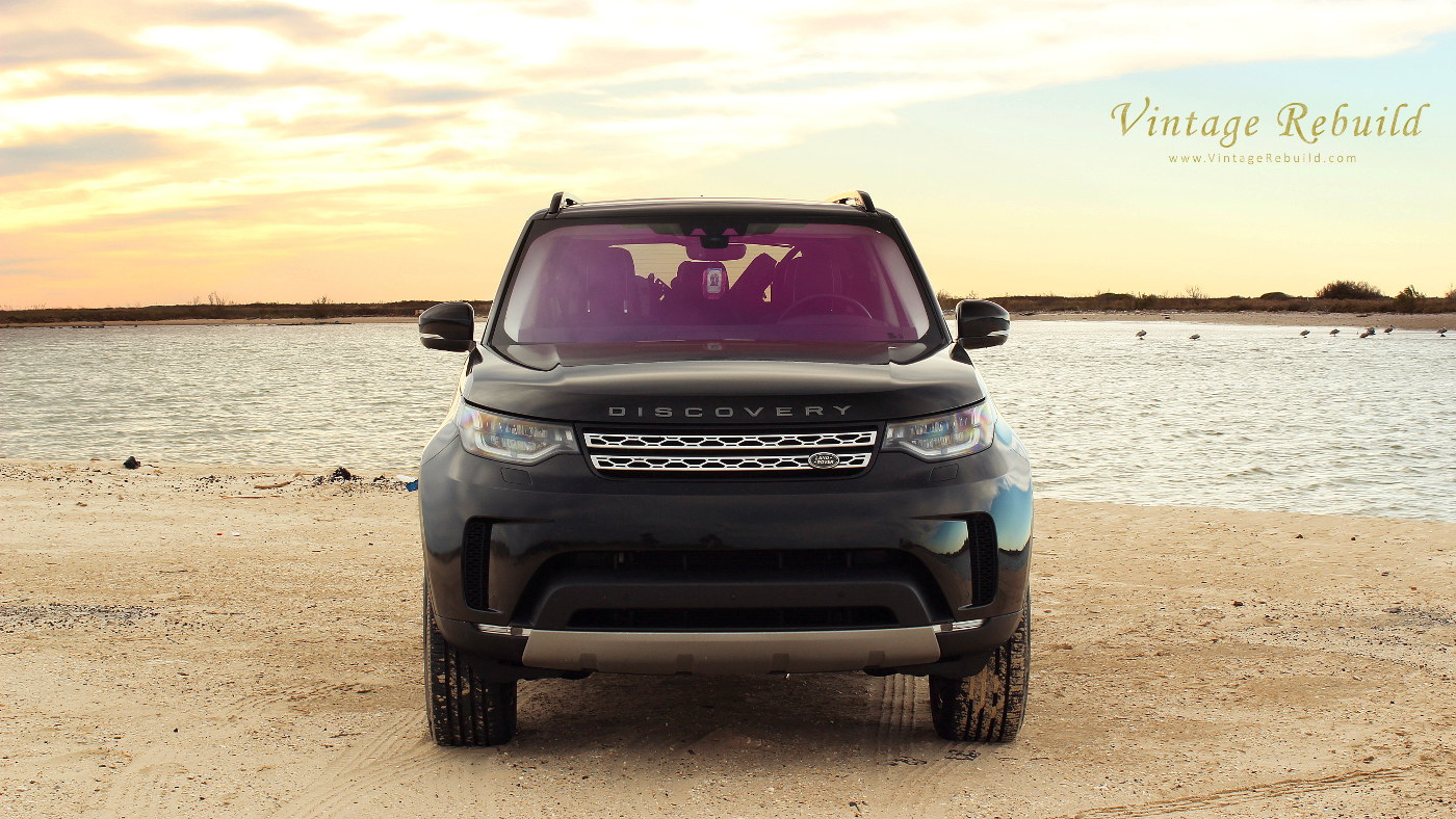 Black 2017 Land Rover Discovery HSE Luxury SUV offroad driving on beach sand at sunset, Jetty Park, Matagorda, Texas.